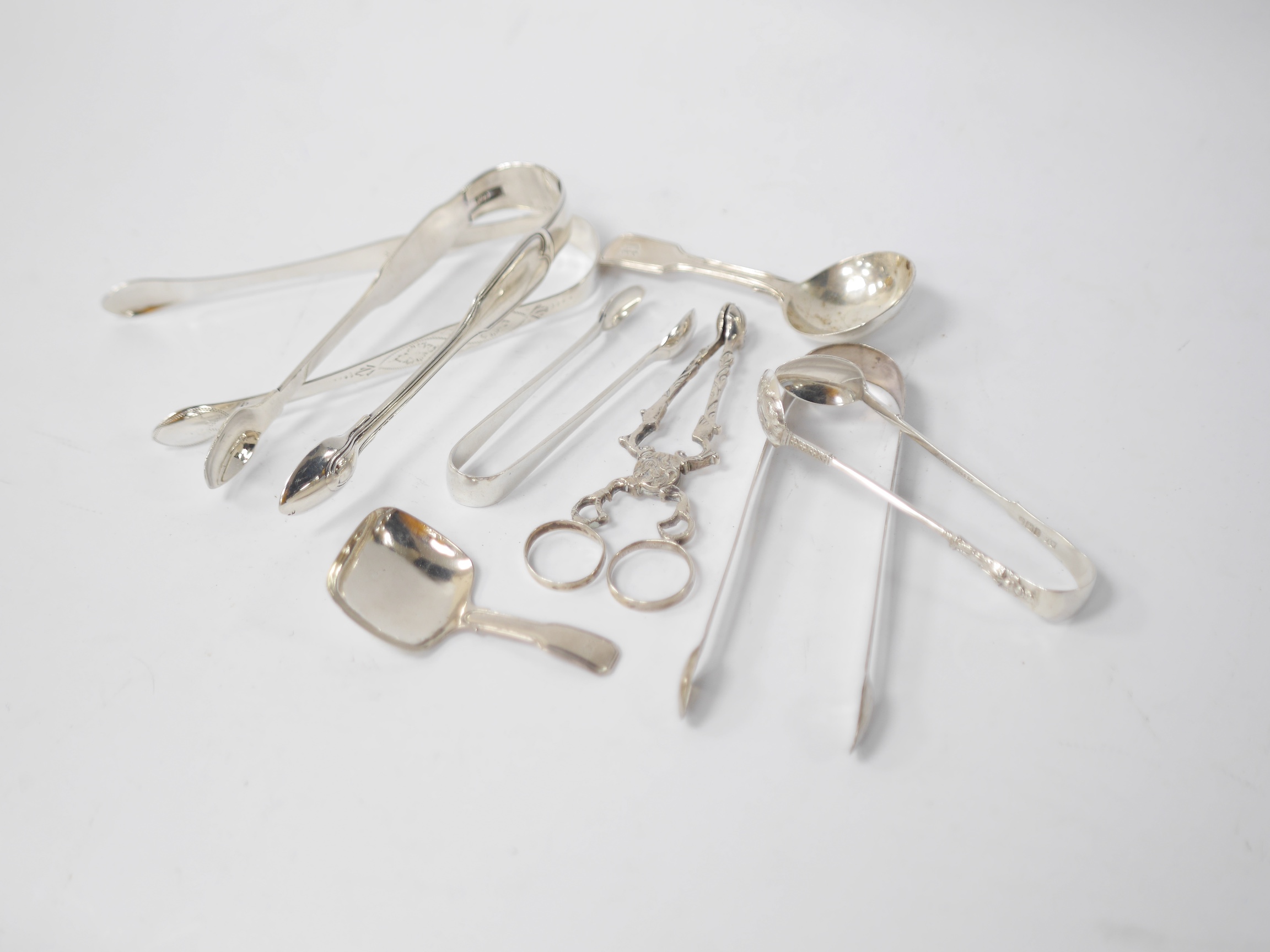 A pair of George III silver sugar tongs by Peter & William Bateman, London, 1807, 14.2cm, three other pairs of silver sugar tongs, one white metal pair, a pair of silver sugar nips and two 19th century silver caddy spoon